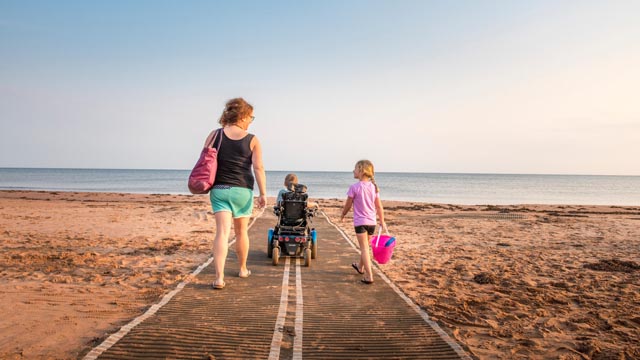 Une famille accessible a besoin de marcher jusqu'à l'eau à Stanhope Beach à l'aide de tapis de mobilité